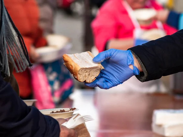 Eine Person mit blauen Nitrilhandschuhen serviert ein Stück Brot — Stockfoto