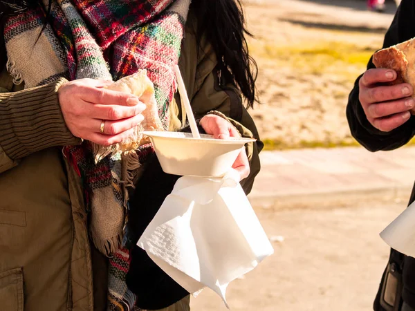 A person eating on the street in a paper plate with a plastic fork at a party