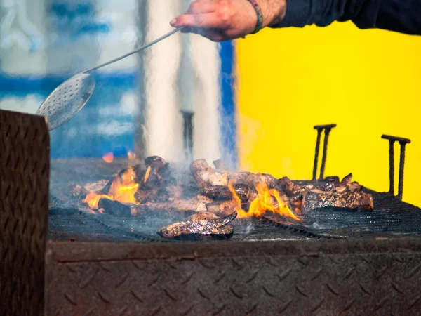 Persona irreconocible cocinando carne de cerdo en una barbacoa en la calle en una fiesta popular en un pueblo en España —  Fotos de Stock