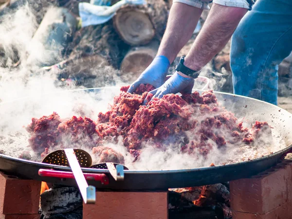 Unerkennbare Person kocht auf der Straße bei einer Volksfeier in einem Dorf in Spanien traditionelle Speisen namens chichas — Stockfoto