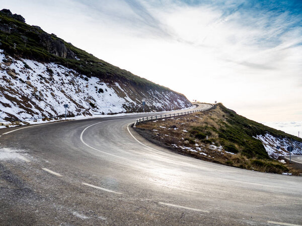 Very closed curve on a dangerous high mountain road with cloudy skies and snow on La Covatilla, Bejar (Salamanca)