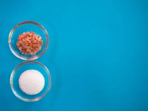 Crystal bowls with himalayan pink salt and common marine salt on a blue background