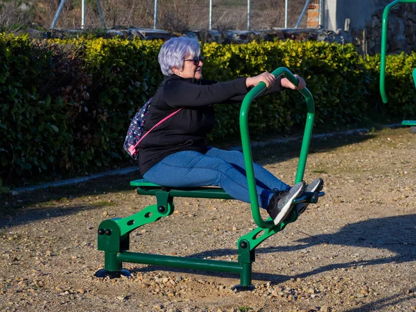 En Senior kvinna med vitt hår öva gymnastik i en bio-hälsosam Park — Stockfoto