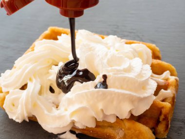 Bir arduvaz plaka üzerinde krem ile Belçikalı Waffle üzerinde düşen çikolata şurubu