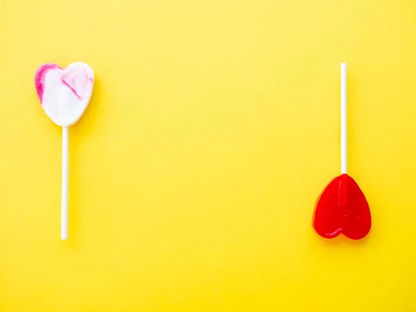 Red lollipop and white and pink lollipops on a yellow background