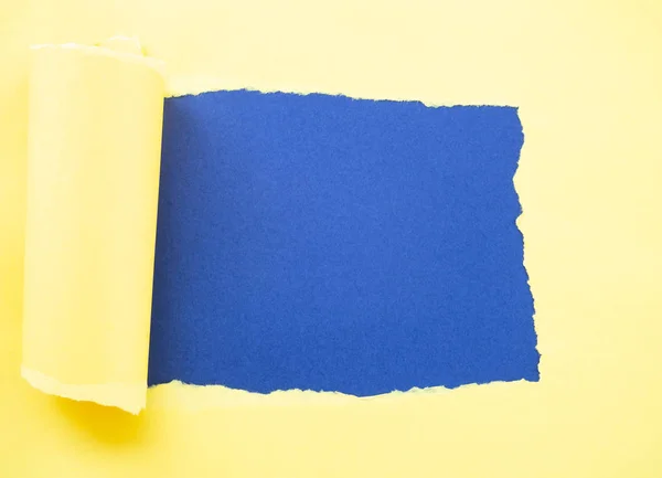 Papel amarelo rasgado isolado em azul — Fotografia de Stock