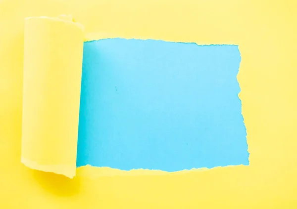 Papel amarelo rasgado isolado em azul — Fotografia de Stock