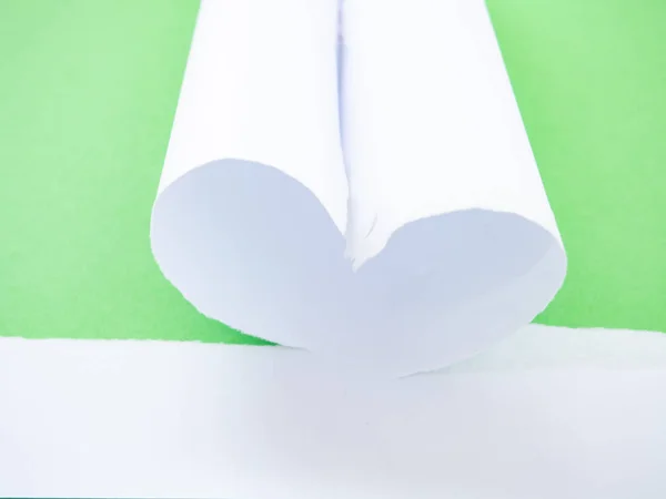 Ein zerrissenes weißes Papier herzförmig isoliert in grün — Stockfoto