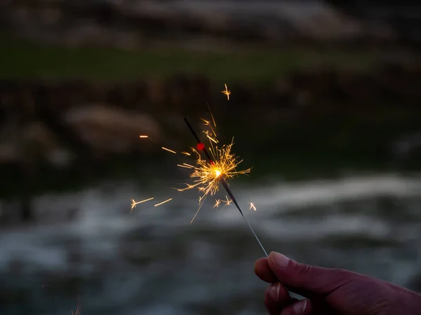 An unrecognizable person with a sparkler sizzling in his hand — Stock Photo, Image