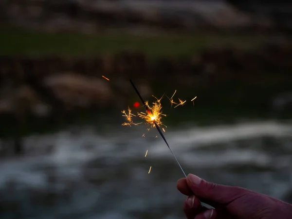 An unrecognizable person with a sparkler sizzling in his hand — Stock Photo, Image