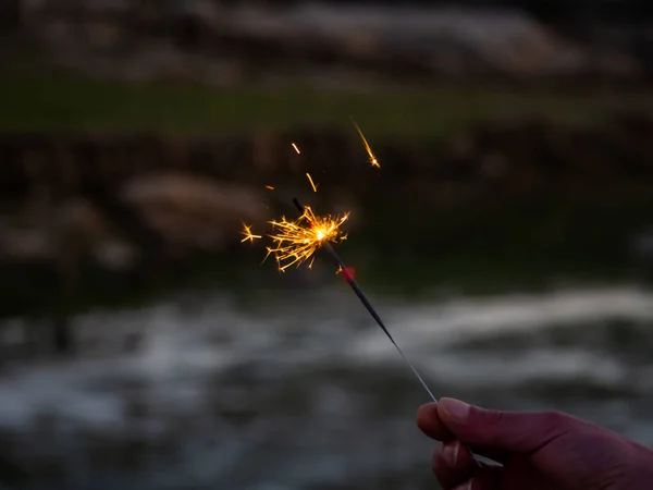 Eine unkenntliche Person mit einer Wunderkerze, die in seiner Hand brutzelt — Stockfoto