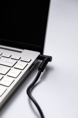 Güç adaptörüyle yüklenen dizüstü bilgisayar beyaz arkaplanda izole edildi