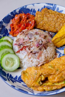 Ev yapımı meşaleli zencefil ya da kecombrang pilavı kızarmış tofu ve tempeh, sambal, omlet ve salatalık ile servis edilir.