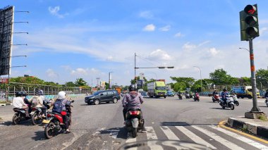 Motosikletli trafik işaretlerini ihlal etti ve bir kavşakta bir zebra kavşağında durdu. Gün boyunca gökyüzü açıktı..