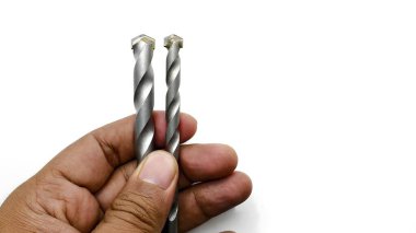 Endonezya eliyle tutulan iki metal matkap ucu beyaz arka planda izole edilmiş.