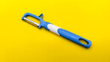 Sarı arka planda mavi meyve ve sebze soyacağı var. köşegen konum