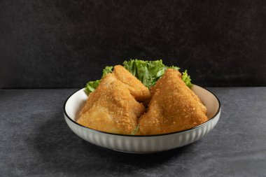 Risol Mayo segitiga ya da Triangle Risol mayonezi beyaz bir kasede servis edilir. Üzerinde taze marul ve koyu kırmızı biber vardır. Ekmek kırıntıları ile Endonezya 'nın lezzetli atıştırmalıklarını gösteriyor.