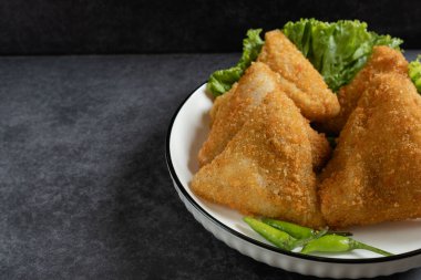 Risol Mayo Segitiga ya da Triangle Risol mayonezini beyaz bir kasede servis edip koyu arkaplanda taze marul ve yeşil biber ile kaplayın. Ekmek kırıntıları ile Endonezya 'nın lezzetli atıştırmalıklarını gösteriyor.