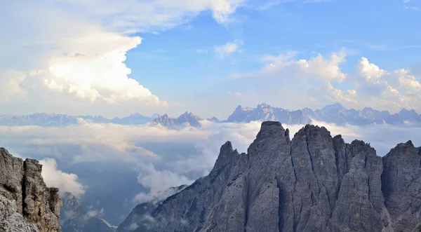 Mountain peaks above white clouds. Blue blue sky with clouds is above the monumental mountain peaks. Dolomite Alps, Italy