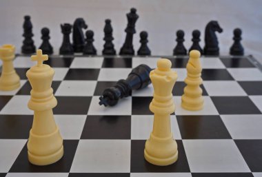 Plastik parçalar ile satranç oyunu. Beyaz satranç taşları kazanan ve bir gemide tek siyah parça diğer siyah yalan söylüyor adettir yönetim kurulu dışında arka planda.