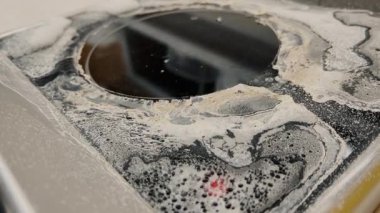 Yanmış gıda tortusu, leke, is ve yağ lekeleriyle kaplı kirli bir sobanın üstü. Aşırı ısınma ve kaynama izleri var. Mutfak kazası temaları ve ev işleri için ideal..