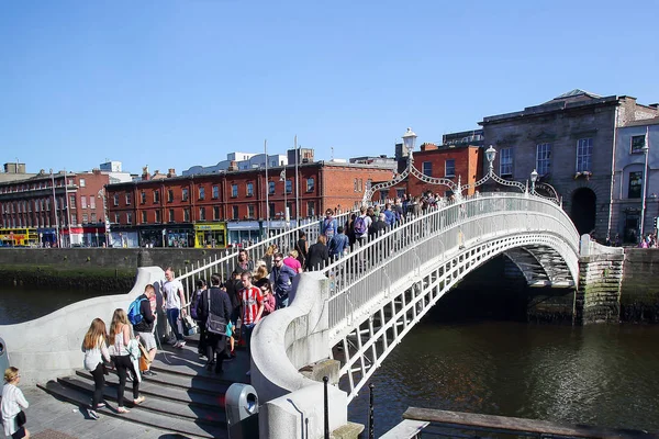People crossing the Ha\'penny Bridge, pedestrian bridge over the river Liffey in Dublin, Ireland