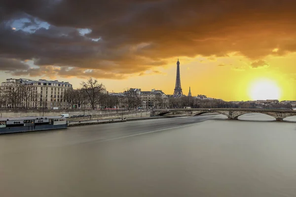 Long exposure photography of sunset in Paris in a cloudy day, with Seine river and Eiffel tower