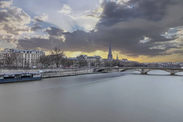 Long exposure photography of sunset in Paris in a cloudy day, with Seine river and Eiffel tower