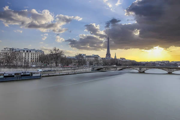 Long exposure photography of sunset in Paris in a cloudy day, with Seine river and Eiffel tower