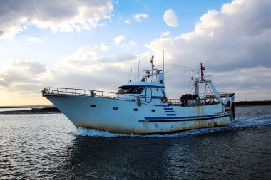 Moon ile gün batımında kıyıya dönen balıkçı teknesi