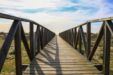 Ahşap geçit üzerinde plaj kum tepeleri. Andalusia, İspanya doğal bir alan içindeki Huelva Beach, plaj yolu