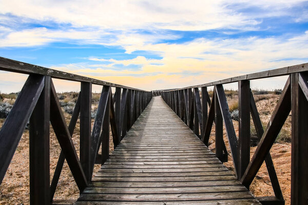 Wooden walkway over the sand dunes to the beach. Beach pathway in Huelva Beach, inside a natural area in Andalusia, Spain
