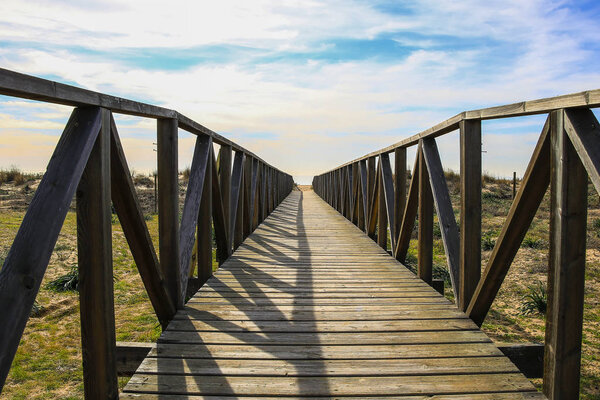 Wooden walkway over the sand dunes to the beach. Beach pathway in Huelva Beach, inside a natural area in Andalusia, Spain