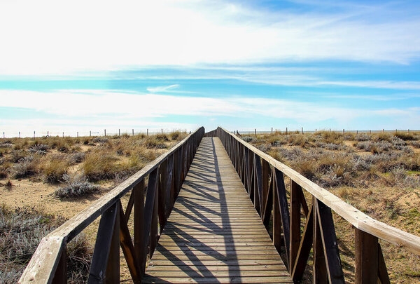 Wooden walkway over the sand dunes to the beach. Beach pathway in Huelva Beach, inside a natural area in Andalusia, Spain