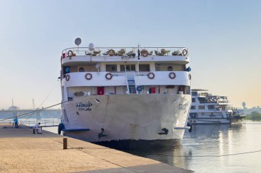 Edfu, Mısır - 16 Eylül 2018: Edfu içinde güneş doğarken, teknenin yolcuları anıtları ziyaret ederken koruyan bir polis demirleyen yüzen otel (turist tekne).