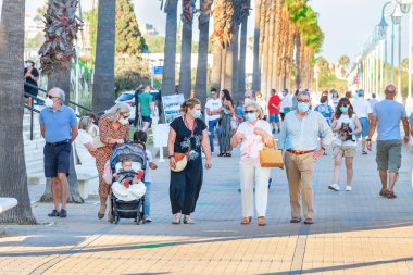 Huelva, İspanya - 3 Haziran 2020: Gün batımında Islantilla 'da yürüyen insanlar, covid-19 nedeniyle koruyucu maske takıyorlar..