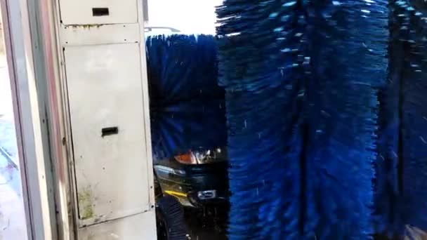 自動洗車プロセス 長い青ブラシ回転し 車を掃除します 窓の下に水が落ちる 車の洗浄アクション — ストック動画