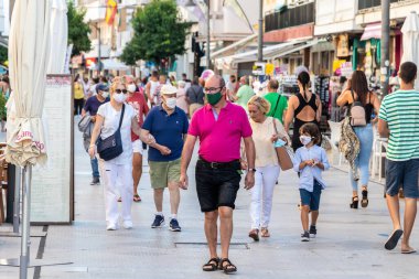 Punta Umbria, Huelva, İspanya - 10 Temmuz 2020: İnsanlar covid-19 nedeniyle koruyucu maske takarak sokakta yürüyorlar. İspanya 'da yeni normal