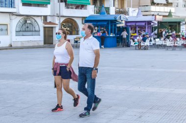 Punta Umbria, Huelva, İspanya - 28 Temmuz 2020: Covid-19 nedeniyle koruyucu maske takan bir çift. İspanya 'da yeni normal