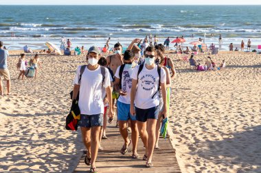Punta Umbria, Huelva, İspanya - 2 Ağustos 2020: İnsanlar plajdan koruyucu veya tıbbi maske takarak çıkıyorlar. Sosyal mesafeyle İspanya 'da yeni normal