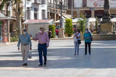 Baeza, Jaen, İspanya - 18 Haziran 2020: İspanya 'daki alarm durumu ve karantina sırasında koruyucu veya tıbbi maske takan yaşlılar.