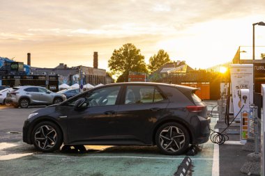 Tallinn, Estonya - 8 Temmuz 2025: Telliskivi Creative City 'deki Elektrum EV istasyonunda çalışan siyah Volkswagen ID.3 elektrikli hatchback' in gün batımı görüntüsü. Sıcak altın ışık ve kentsel çevre dostu titreşim