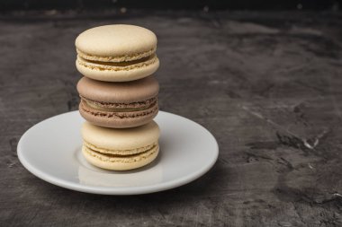 Lezzetli, çerezleri macarons plaka üzerinde. Kahve ve çikolata tadı. Koyu arka plan, kopya alanı
