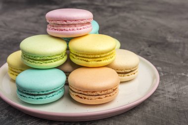 Tatlı renkli macarons plaka üzerinde. Koyu arka plan 