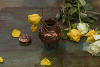Bir yağmur sonra boyalı bir tabloda bir bronz vazo içinde sarı gül 
