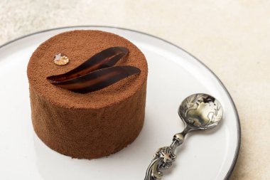 Bir tabakta çikolatalı kek keçeleşmiş çiğ ve çikolata yaprakları bir damla ile. El yapımı. Hafif bir arka plan karşı 