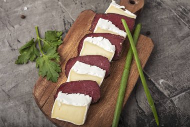 Sertleştirilmiş et ve peynir beyaz kalıp ile. Dilim peynir ve yeşillikleri ile ahşap bir gemide sertleştirilmiş et. Yukarıdan görüntülemek