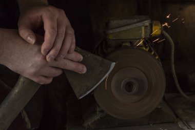 Değirmeni adam elinde balta keskinleştirme. Koyu arka plan