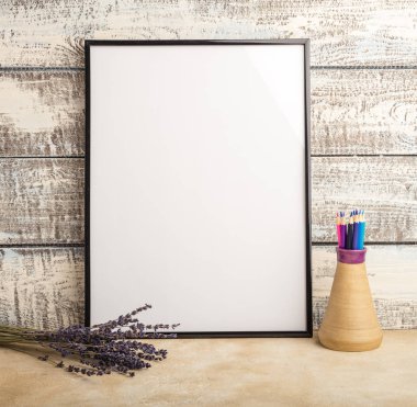 Kadar bir duvar ahşap kurullarının bir boş çerçeve posterin alay et. Lavanta ve bir vazo renkli kalemler ile oluşan