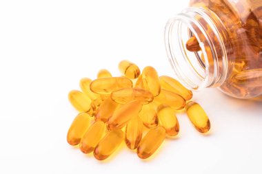 Bir şişe beyaz bir arka plan üzerinde dışarı dökülmesini omega 3 balık yağı kapsülleri. Kopya alanı
